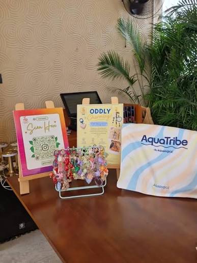 A table with a QR code sign, a keychain charm display and a branded hamper pouch
